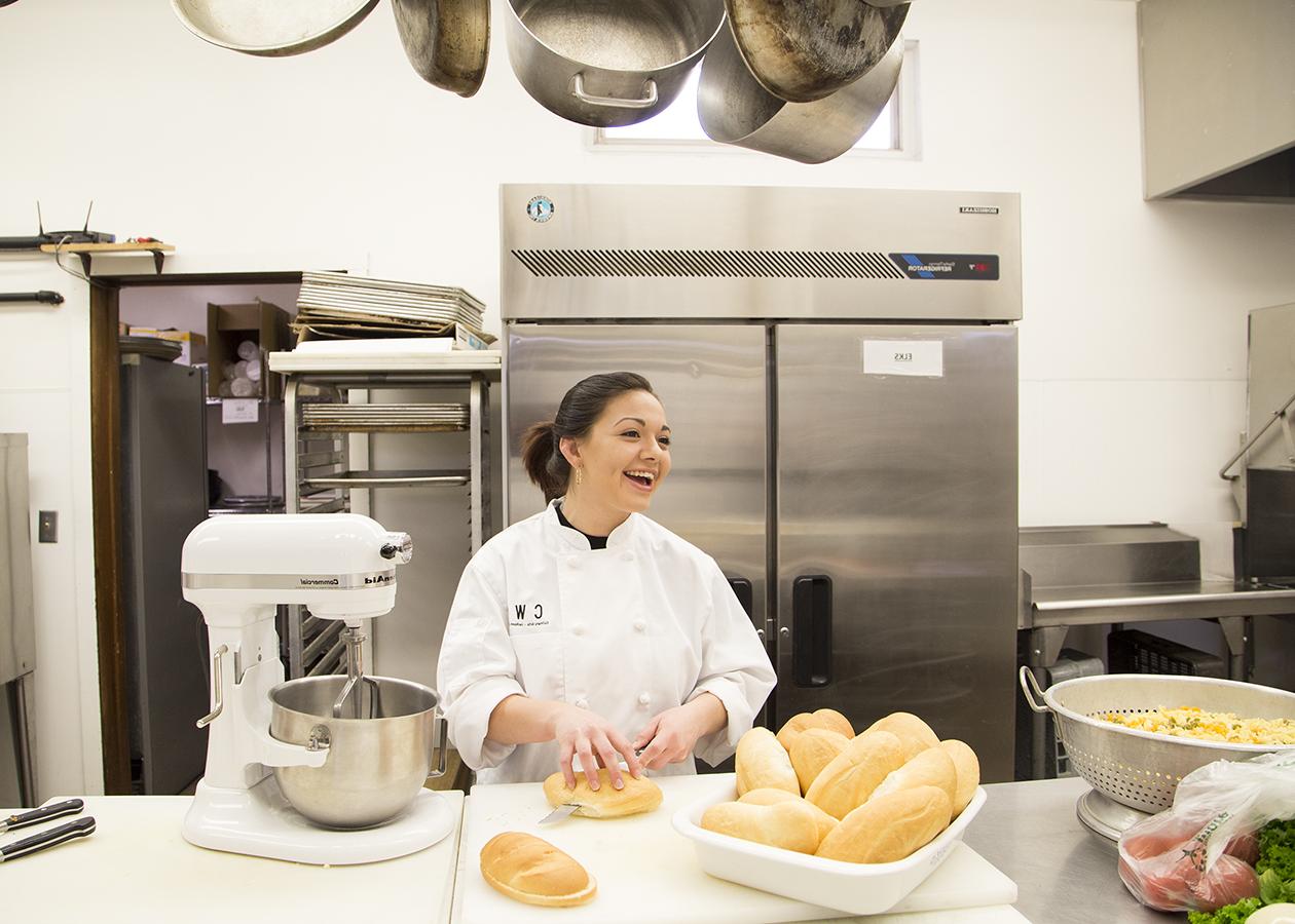 一个烹饪专业的女学生在厨房里切面包
